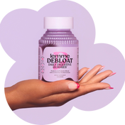Hand holding a bottle of 'Lemme Debloat Daily Digestive Gummies' against a purple heart-shaped background