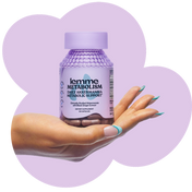 Hand holding a bottle of lemme Metabolism supplement against a purple background